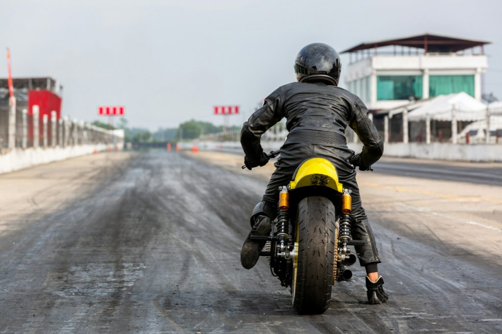 Man on motorbike on the road racing track riding, Biker sitting on motorcycle wearing helmet.